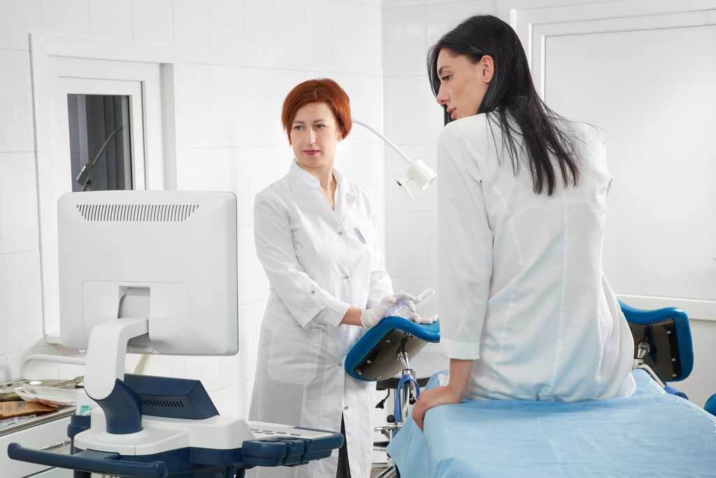 Gynecologist examines patient on table as they look at the computer monitor Complete Healthcare Primary Care and Gynecology