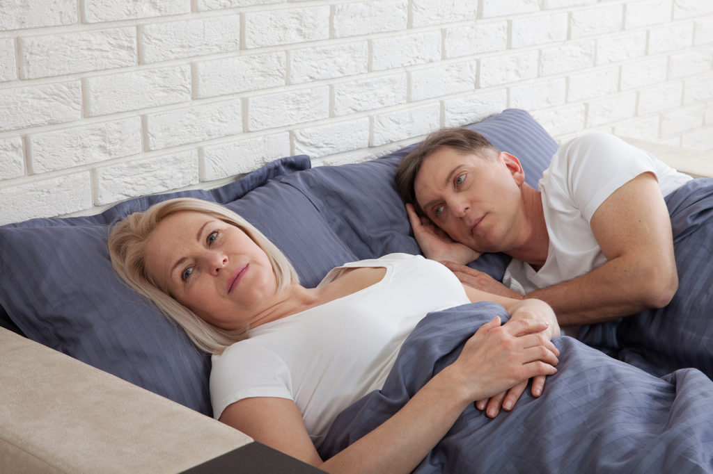 Older woman in bed with her spouse going through menopause and not wanting to be intimate with her husband Complete Healthcare Primary Care and Gynecology