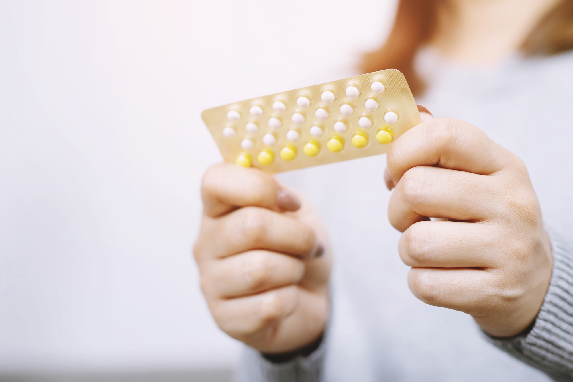 Closeup of woman holding brith control pills Complete Healthcare Primary Care and Gynecology