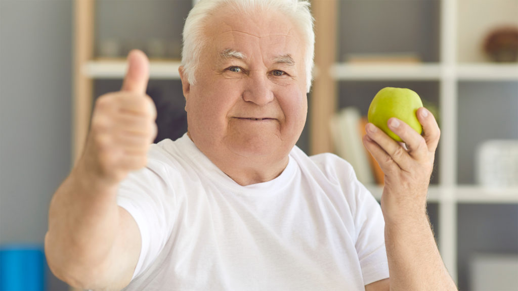 Older man giving thumbs up and holding an apple Complete Healthcare Primary Care and Gynecology