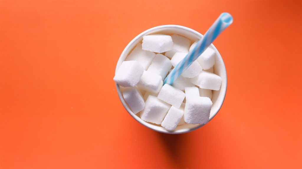 Overhead view of cup on orange table full of sugar cubes and a straw Complete Healthcare Primary Care and Gynecology