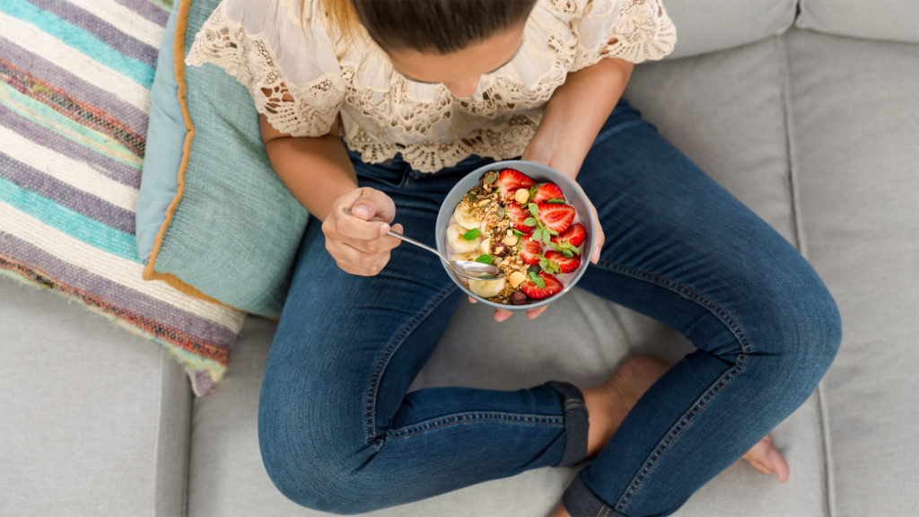 Overheadview of woman holding bowl with fruit and grains eating a healthy breakfast Complete Healthcare Primary Care and Gynecology