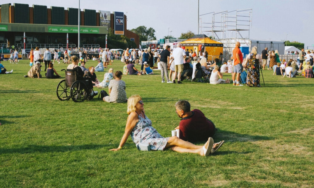 people of various ages sitting outside on a sunny day at the park