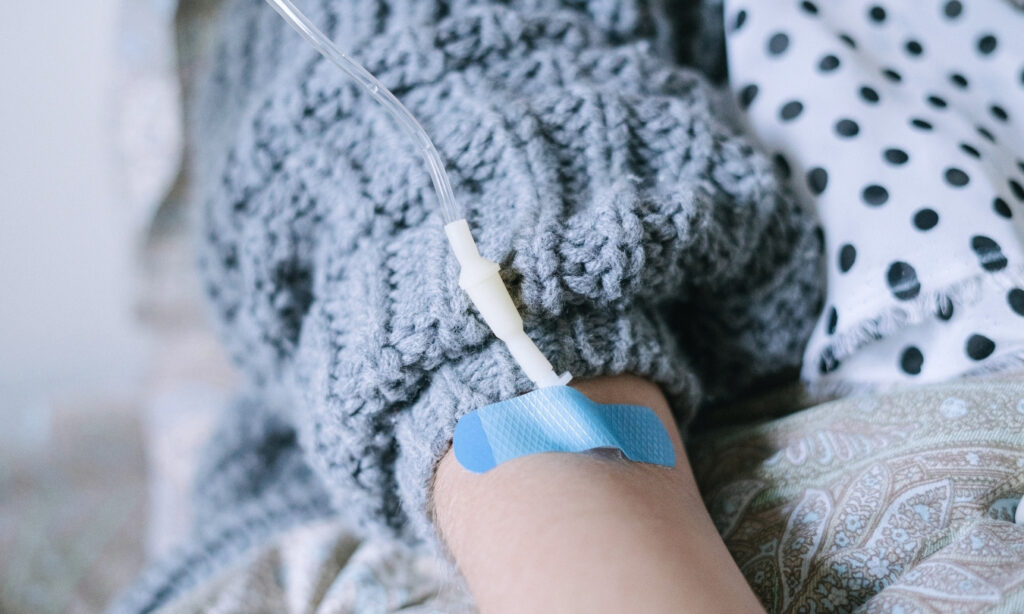 IV drip inserted in the arm of a person wearing a knitted sweater