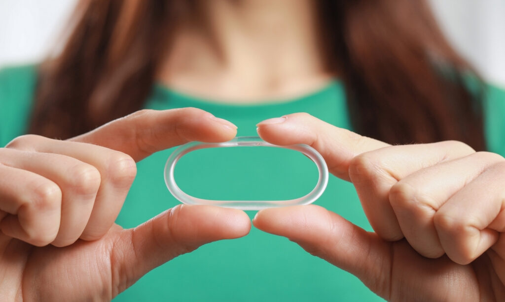 Woman Holding Diaphragm Vaginal Contraceptive Ring on Blurred Background